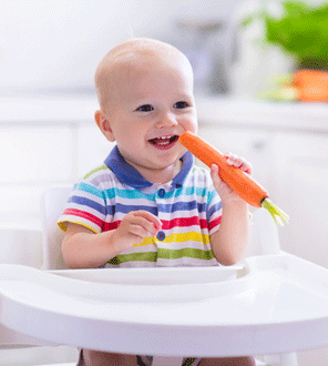 Ein Baby isst eine Karotte